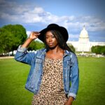 woman in blue denim jacket standing on green grass field during daytime